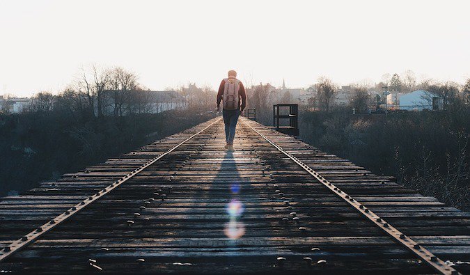 A guy walking down railroad tracks alone