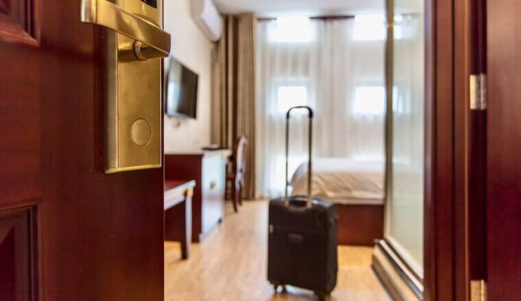 A suitcase in a spacious hotel room as the door opens