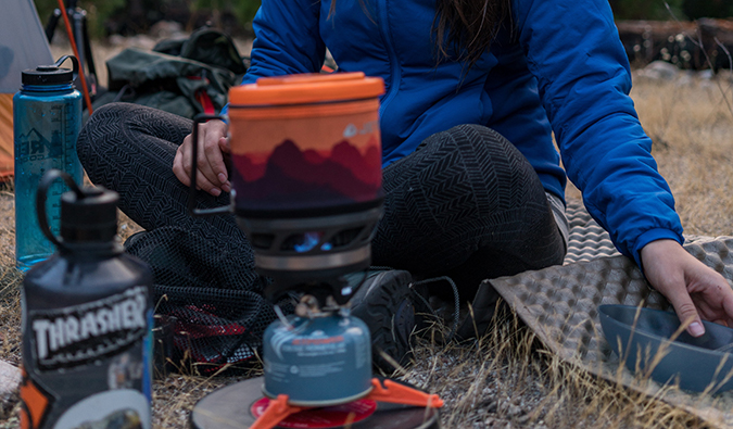 a woman setting up a campfire while camping