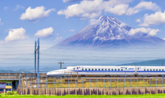 A bullet train crosses in front of the famous Mount Fuji in the background in Japan