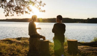 Two travelers having a conversation by a lake