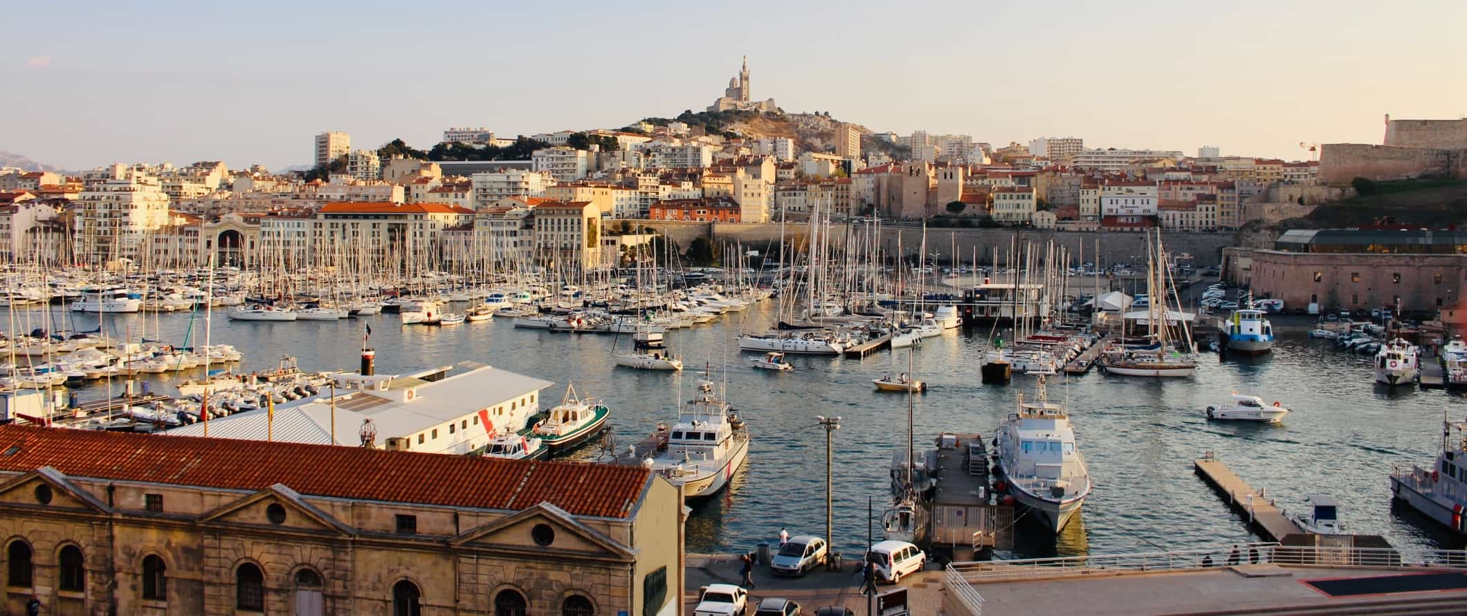 The old port filled with sailboats, with the city of Marseille rising up behind it in France