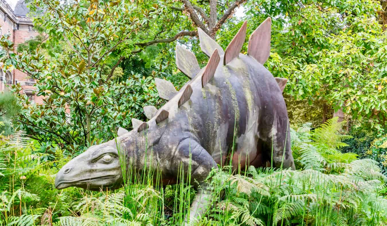 A dinosaur statue in tall grass in Paris, France