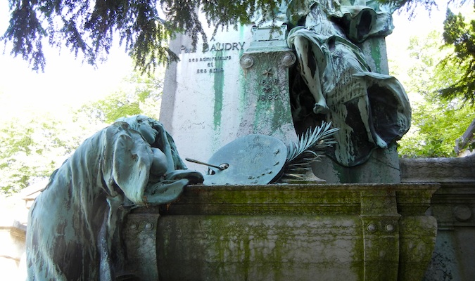 Weathered mourning statues at Pere Lachaise cemetery in Paris, France 