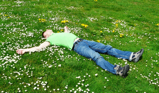 man laying on his back on grass covered in daisies