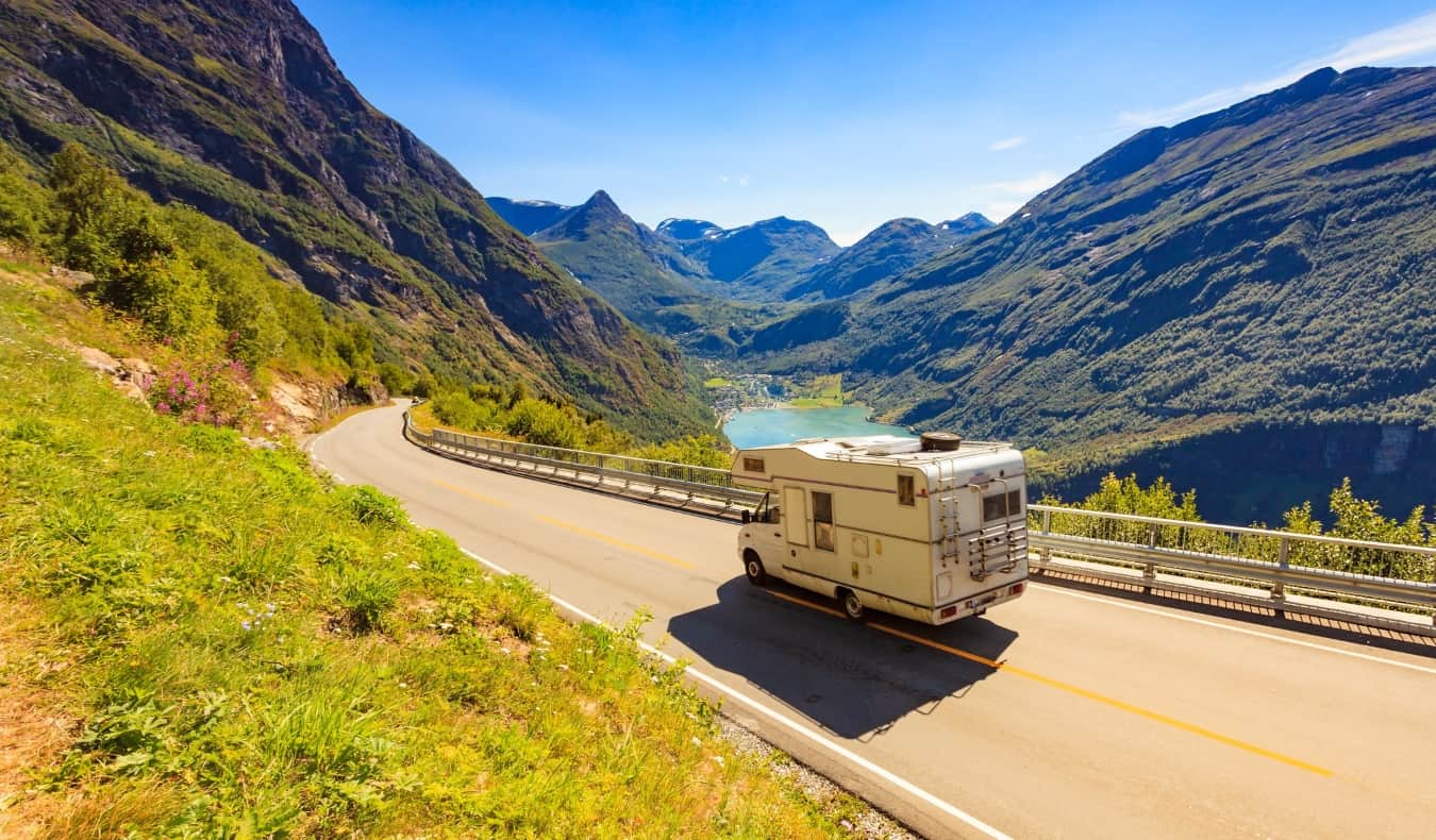 A RV drives through a winding road through a picturesque mountainous landscape