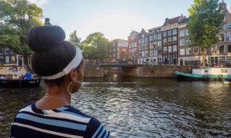 Senitra, a solo black female traveler posing near a canal in Europe