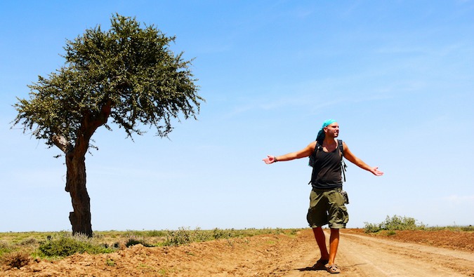 Tomislav, a travel blogger and budget traveler, stands next to a lone tree in Tanzania, Africa