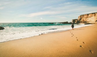 A solo female traveler walking alone on a sandy beach