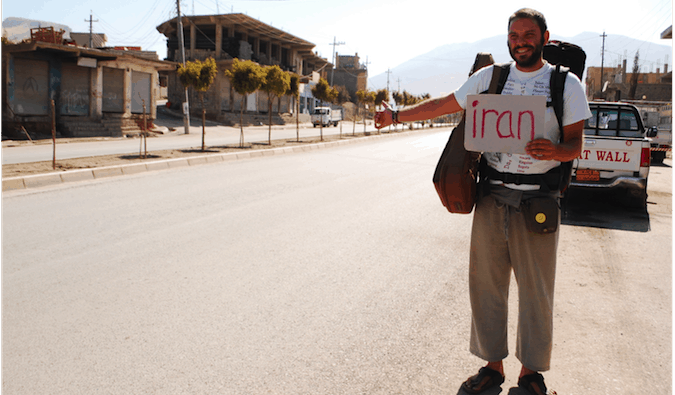 A solo backpacker hitchhiking in Iraq while holding a sign